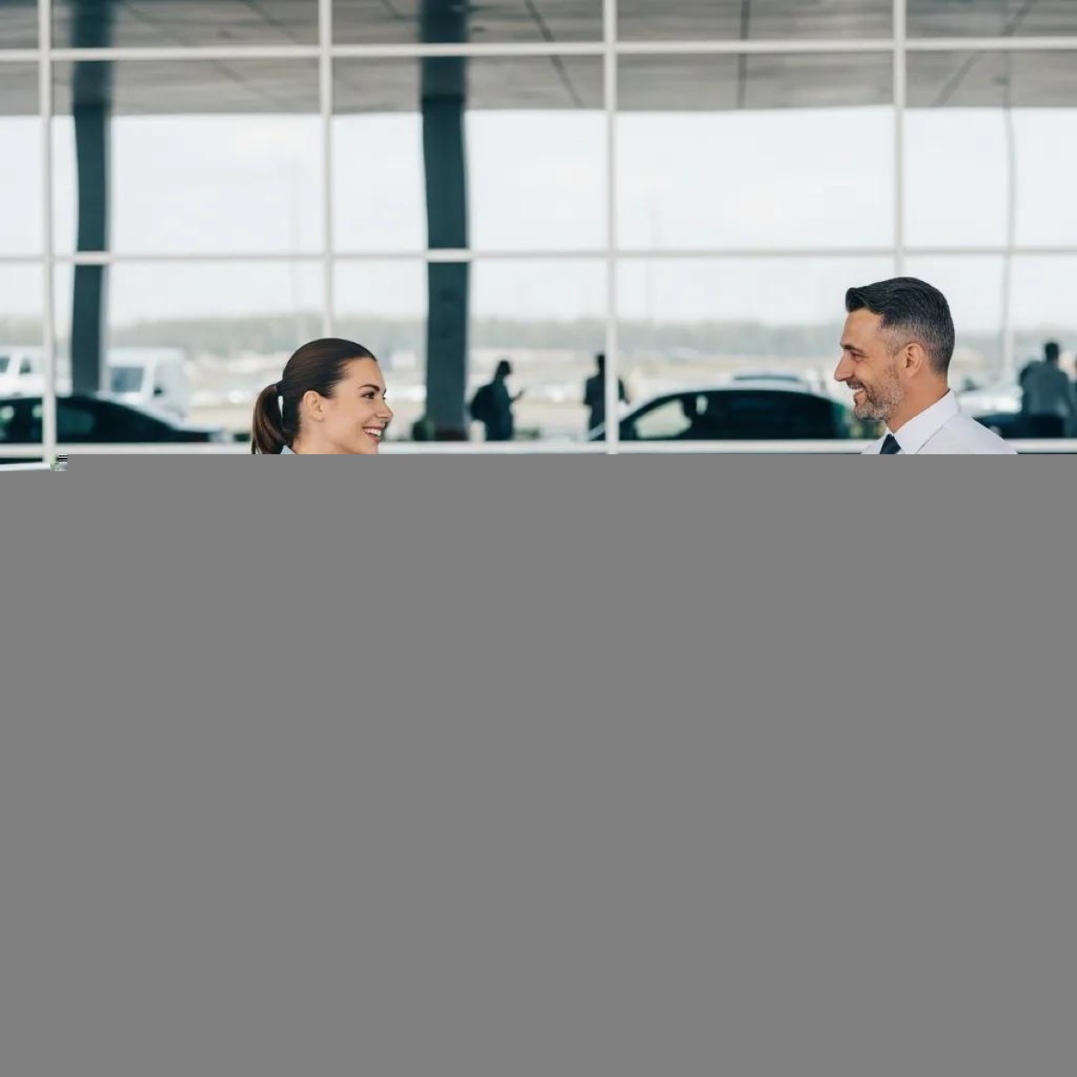 First-time traveler happily engaging with a professional driver at the airport for transfer services